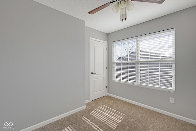 carpeted spare room with a textured ceiling, baseboards, and a ceiling fan