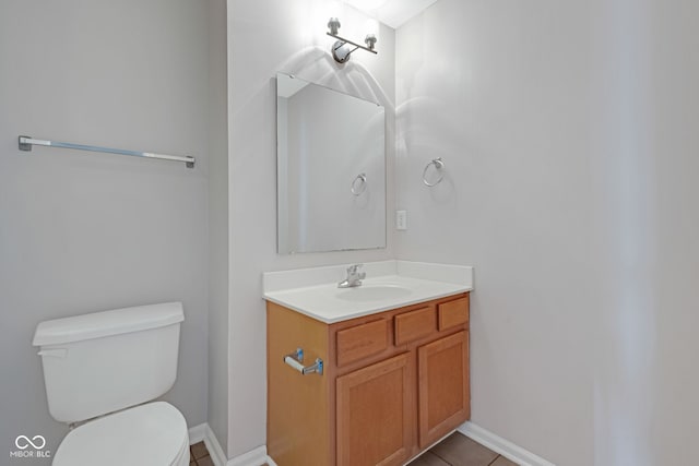 half bathroom featuring baseboards, vanity, toilet, and tile patterned floors