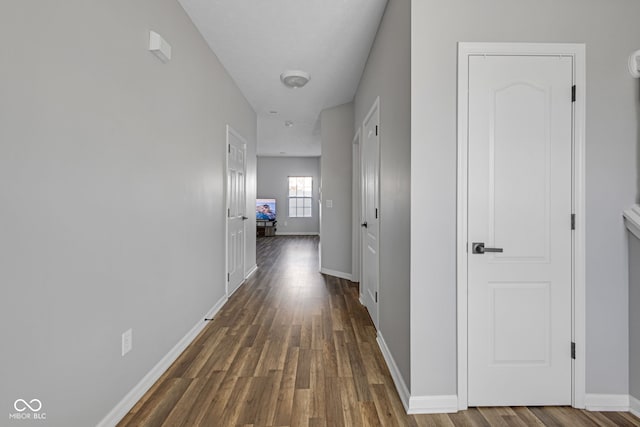 corridor featuring baseboards and wood finished floors