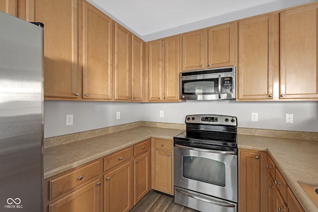 kitchen featuring stainless steel appliances, dark wood-style flooring, and light countertops