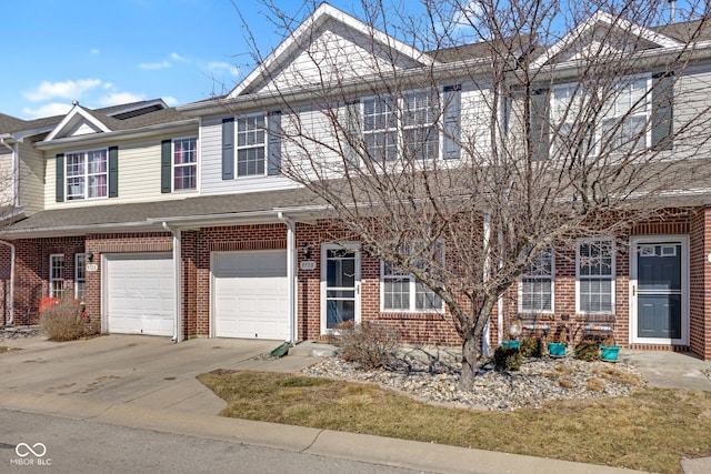 multi unit property with a garage, roof with shingles, concrete driveway, and brick siding