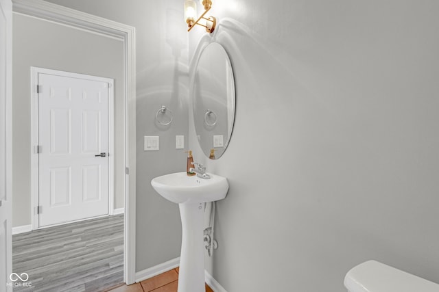 bathroom with toilet, tile patterned flooring, baseboards, and a sink