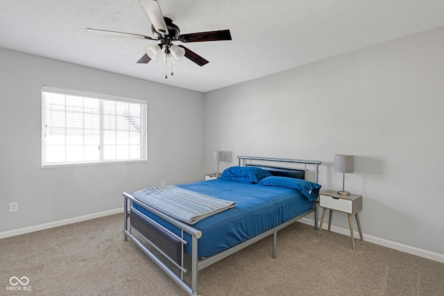 carpeted bedroom with a textured ceiling, ceiling fan, and baseboards