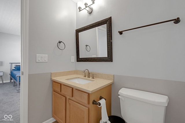 bathroom with baseboards, vanity, and toilet