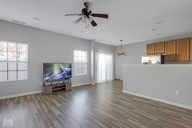 unfurnished living room featuring dark wood-style flooring, visible vents, and baseboards