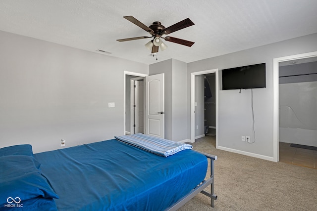 bedroom featuring carpet floors, visible vents, a spacious closet, a textured ceiling, and baseboards