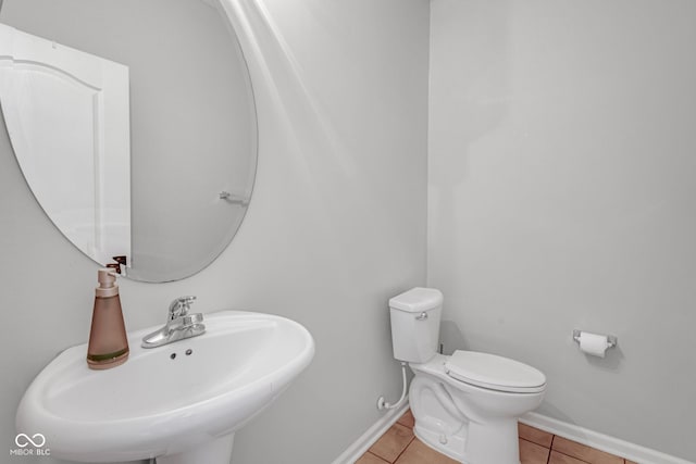 bathroom with toilet, baseboards, a sink, and tile patterned floors