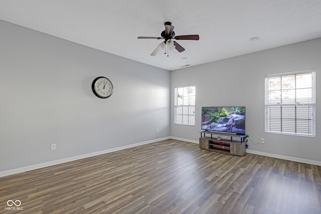 unfurnished living room with ceiling fan, baseboards, and wood finished floors