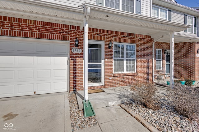 entrance to property with brick siding and an attached garage