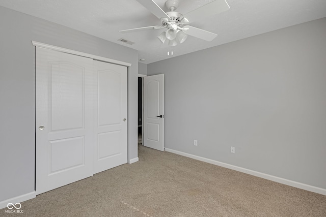 unfurnished bedroom featuring carpet floors, a closet, visible vents, a ceiling fan, and baseboards