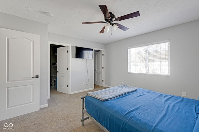 bedroom featuring a ceiling fan, light colored carpet, a textured ceiling, and baseboards