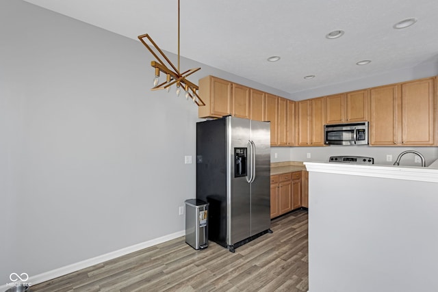 kitchen with light wood-style flooring, recessed lighting, a sink, baseboards, and appliances with stainless steel finishes