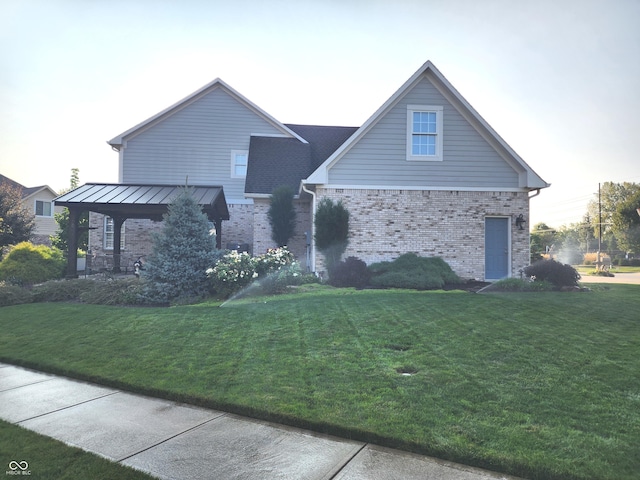 view of front of house featuring a front yard, a standing seam roof, brick siding, and metal roof