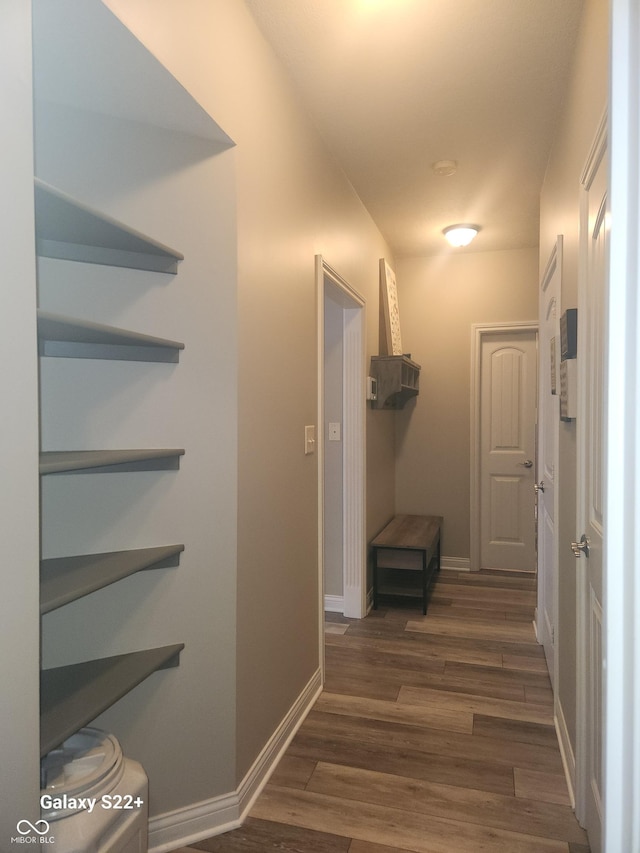 corridor featuring baseboards and dark wood finished floors