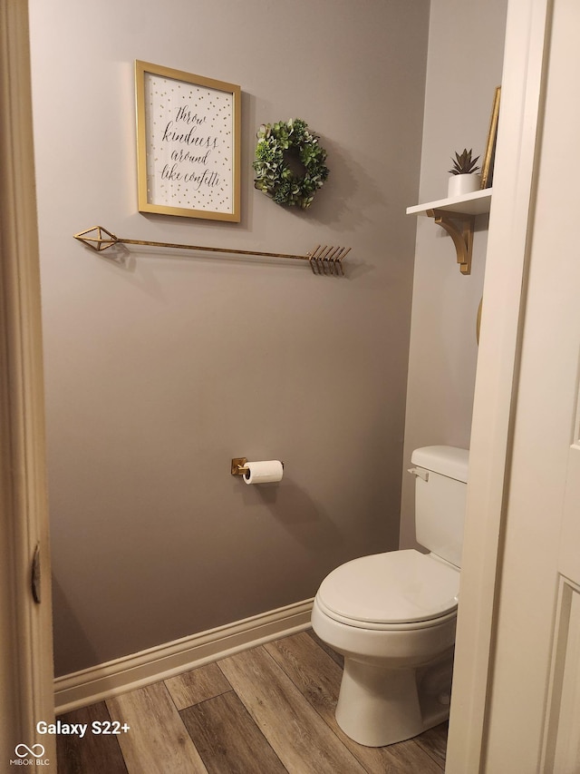 bathroom with toilet, baseboards, and wood finished floors