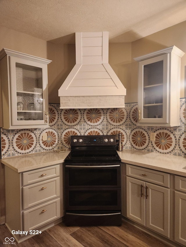 kitchen featuring light countertops, range with two ovens, dark wood-type flooring, and custom range hood