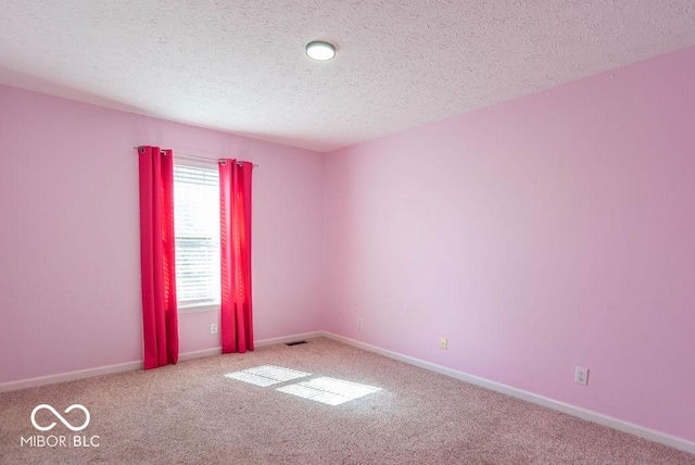 unfurnished room with a textured ceiling, carpet, and baseboards