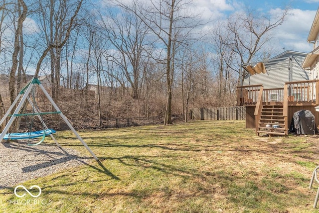 view of yard with a playground, fence, a deck, and stairs