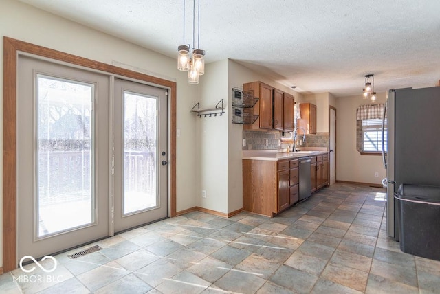 kitchen with visible vents, brown cabinetry, stainless steel appliances, light countertops, and backsplash