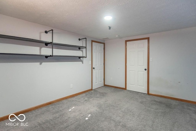 below grade area featuring carpet flooring, a textured ceiling, and baseboards