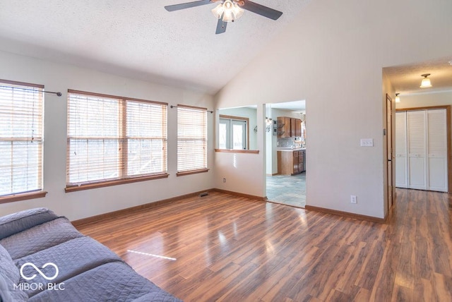 unfurnished living room with a ceiling fan, baseboards, a textured ceiling, and wood finished floors