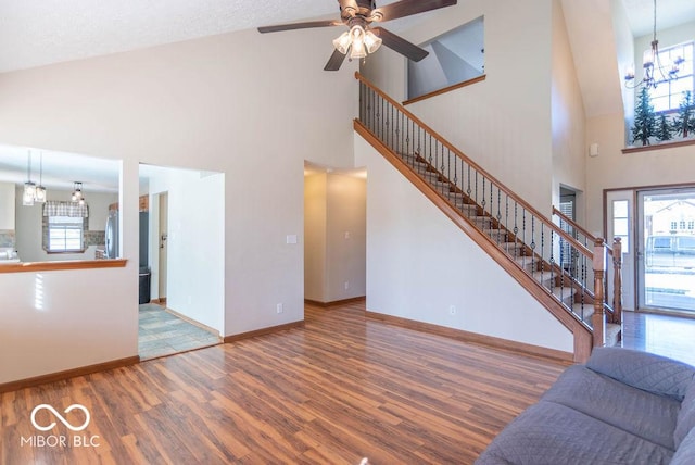 unfurnished living room featuring stairs, a healthy amount of sunlight, baseboards, and wood finished floors