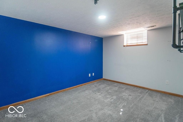 spare room with a textured ceiling, carpet flooring, visible vents, and baseboards