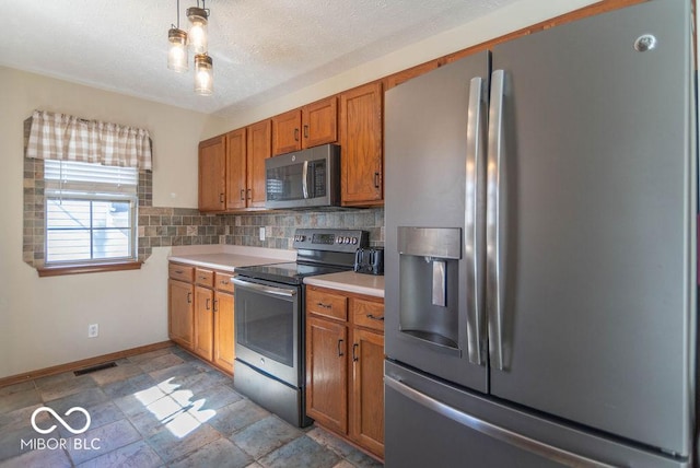 kitchen featuring stainless steel appliances, visible vents, light countertops, brown cabinets, and tasteful backsplash