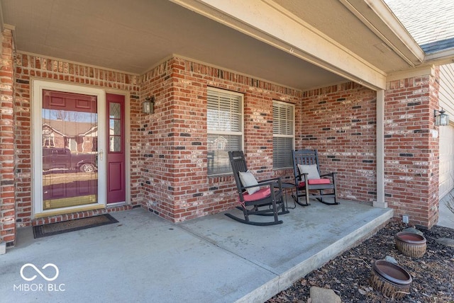 view of exterior entry with covered porch and brick siding