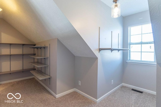 bonus room with carpet floors, visible vents, and a textured ceiling