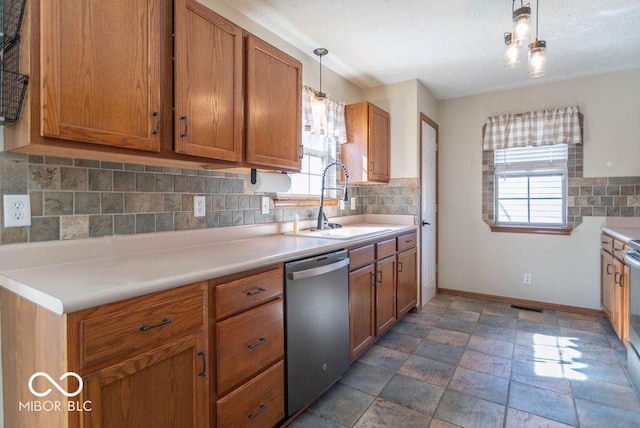 kitchen featuring brown cabinets, a healthy amount of sunlight, a sink, and stainless steel dishwasher