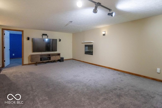 unfurnished living room featuring a garage, a glass covered fireplace, carpet flooring, and baseboards