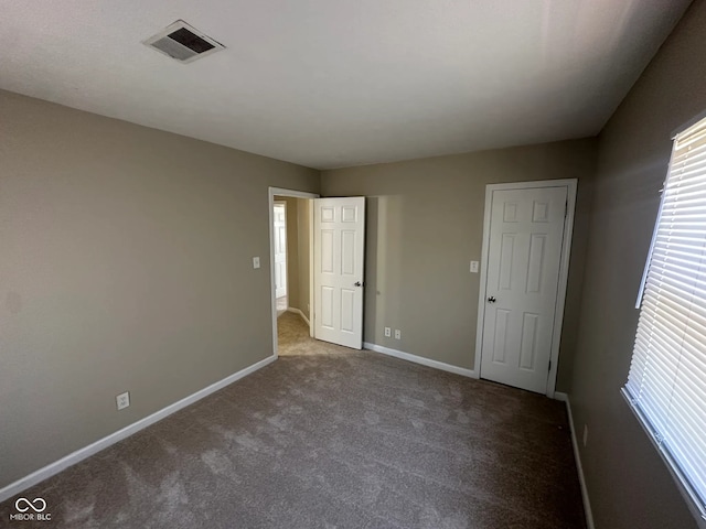 unfurnished bedroom with visible vents, carpet flooring, and baseboards