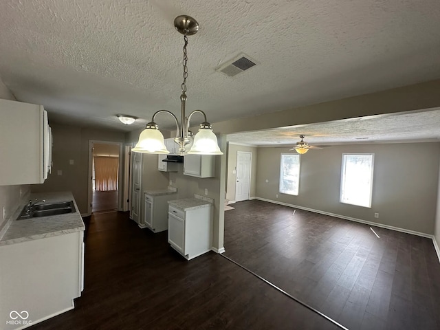 kitchen with visible vents, baseboards, a textured ceiling, white cabinetry, and a ceiling fan