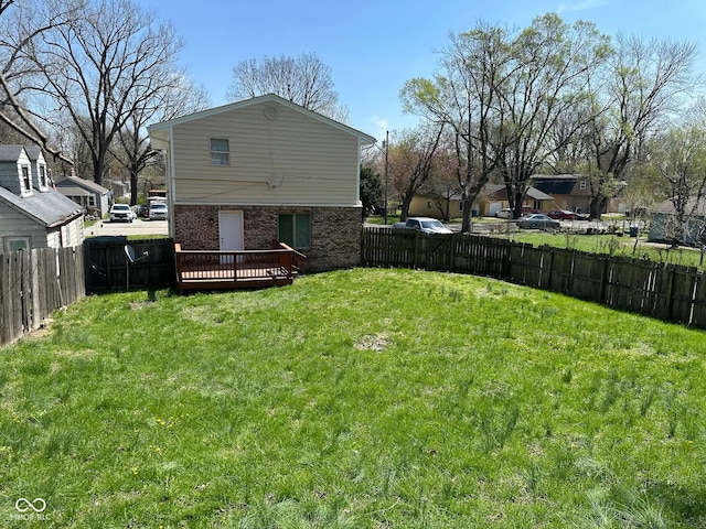 back of property featuring a yard, brick siding, a wooden deck, and a fenced backyard