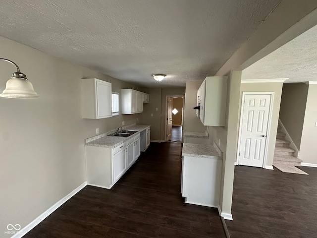 kitchen with baseboards, light countertops, a textured ceiling, and dark wood-type flooring