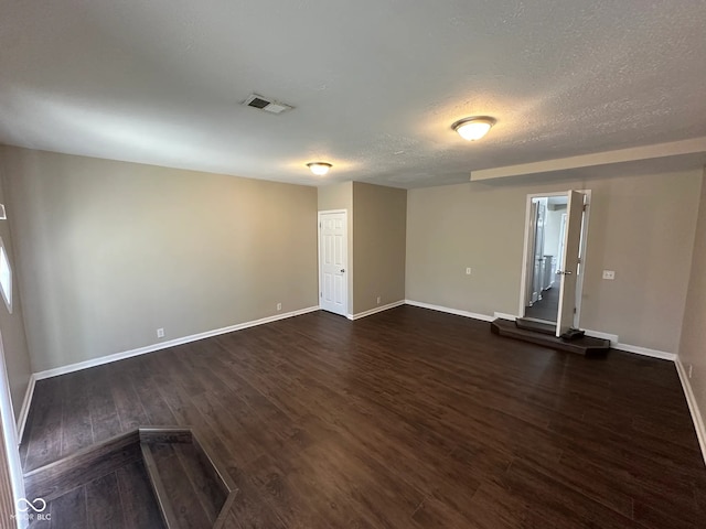 interior space featuring visible vents, a textured ceiling, baseboards, and dark wood-type flooring