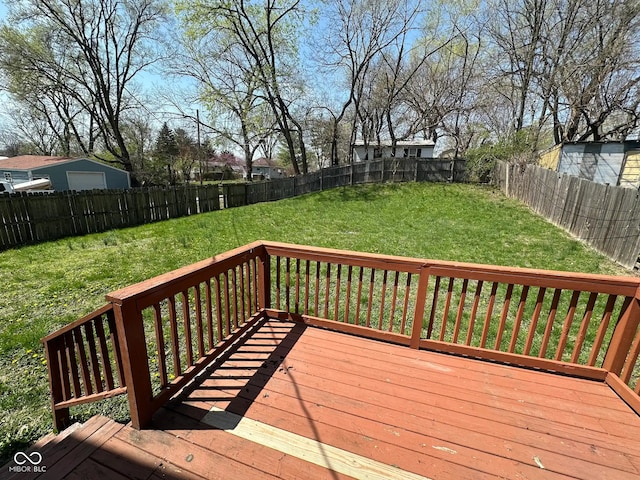 deck with a fenced backyard, a detached garage, and a yard
