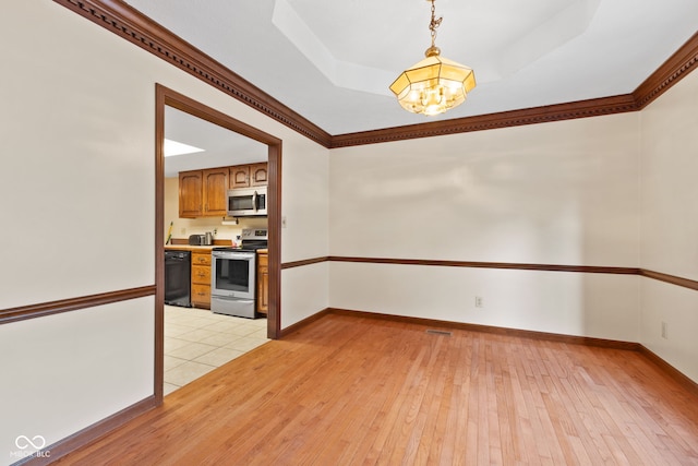 interior space featuring a chandelier, baseboards, ornamental molding, light wood finished floors, and a raised ceiling