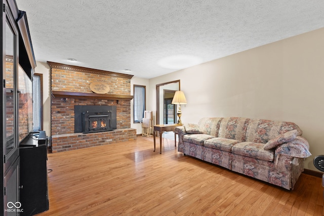 living room with a brick fireplace, wood-type flooring, and a textured ceiling