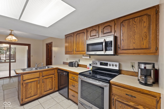 kitchen with stainless steel appliances, a peninsula, a sink, light countertops, and brown cabinets