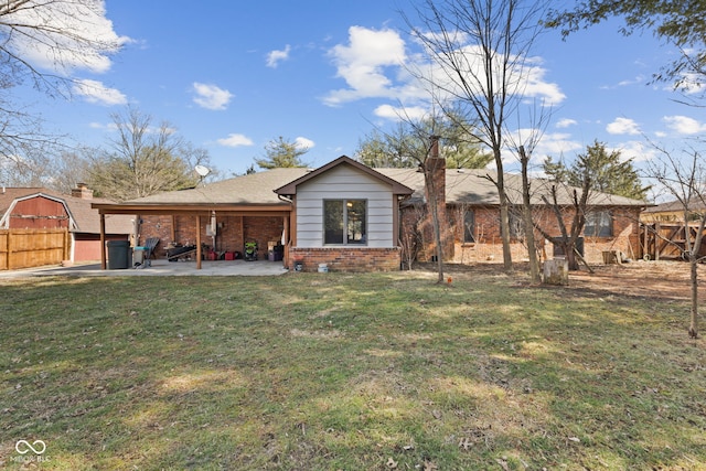 rear view of house with a patio area, brick siding, a lawn, and fence