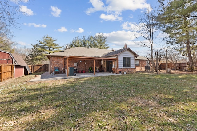 back of property with a lawn, a fenced backyard, a chimney, a patio area, and brick siding