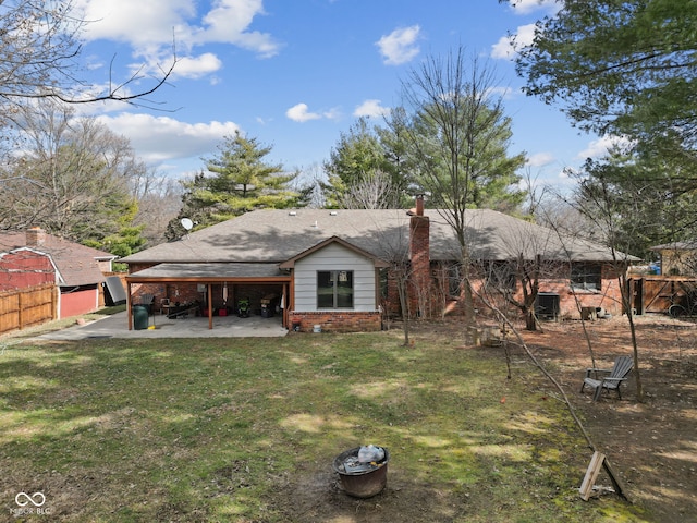 rear view of property featuring a lawn, a patio, a chimney, fence, and brick siding