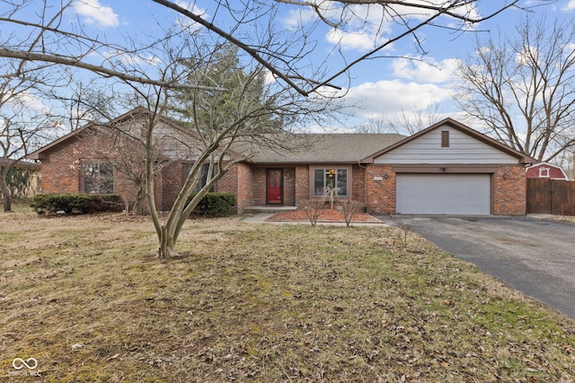 ranch-style home featuring brick siding, an attached garage, fence, driveway, and a front lawn