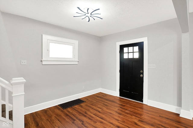 foyer featuring visible vents, dark wood finished floors, a textured ceiling, and baseboards