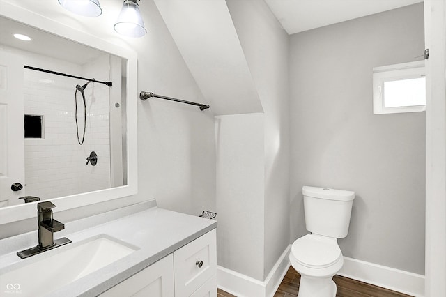 full bath featuring baseboards, toilet, wood finished floors, a tile shower, and vanity