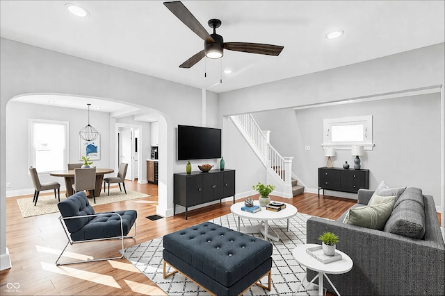 living room with arched walkways, recessed lighting, baseboards, stairs, and light wood-type flooring