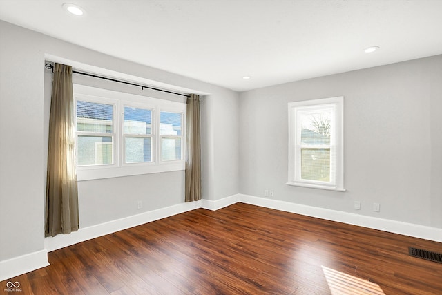 unfurnished room with dark wood-style flooring, visible vents, and plenty of natural light