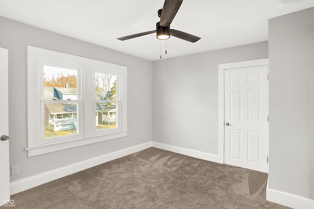 unfurnished room with dark colored carpet, ceiling fan, and baseboards